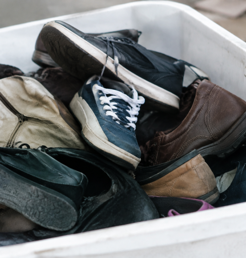 Souliers empiles dans bac blanc de recyclage